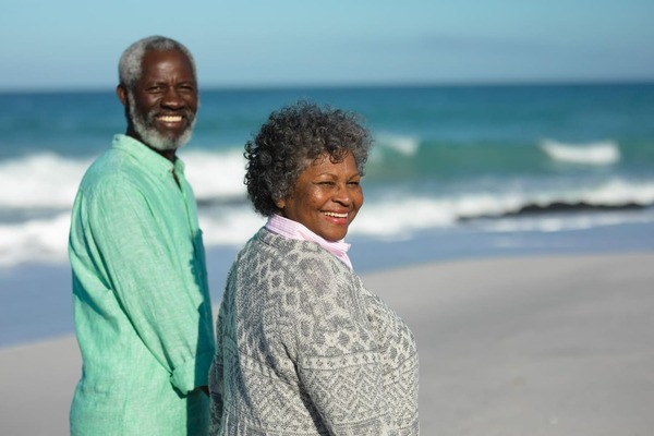 older black couple smiling together by the beach