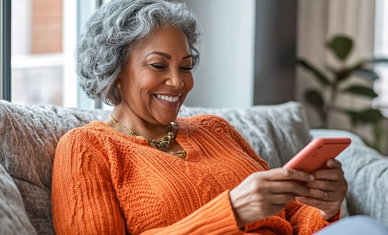 Black woman over 50 using a dating app on her phone